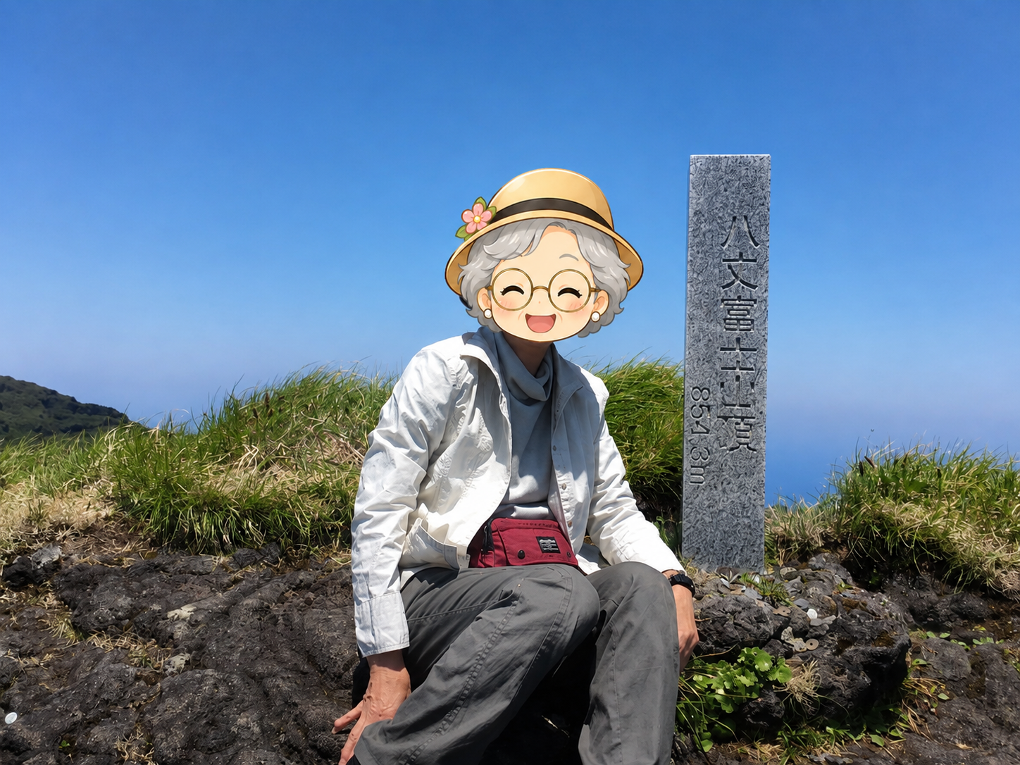 八丈富士山頂の標柱の横での登頂記念写真(顔はキャラクターのスタンプ)