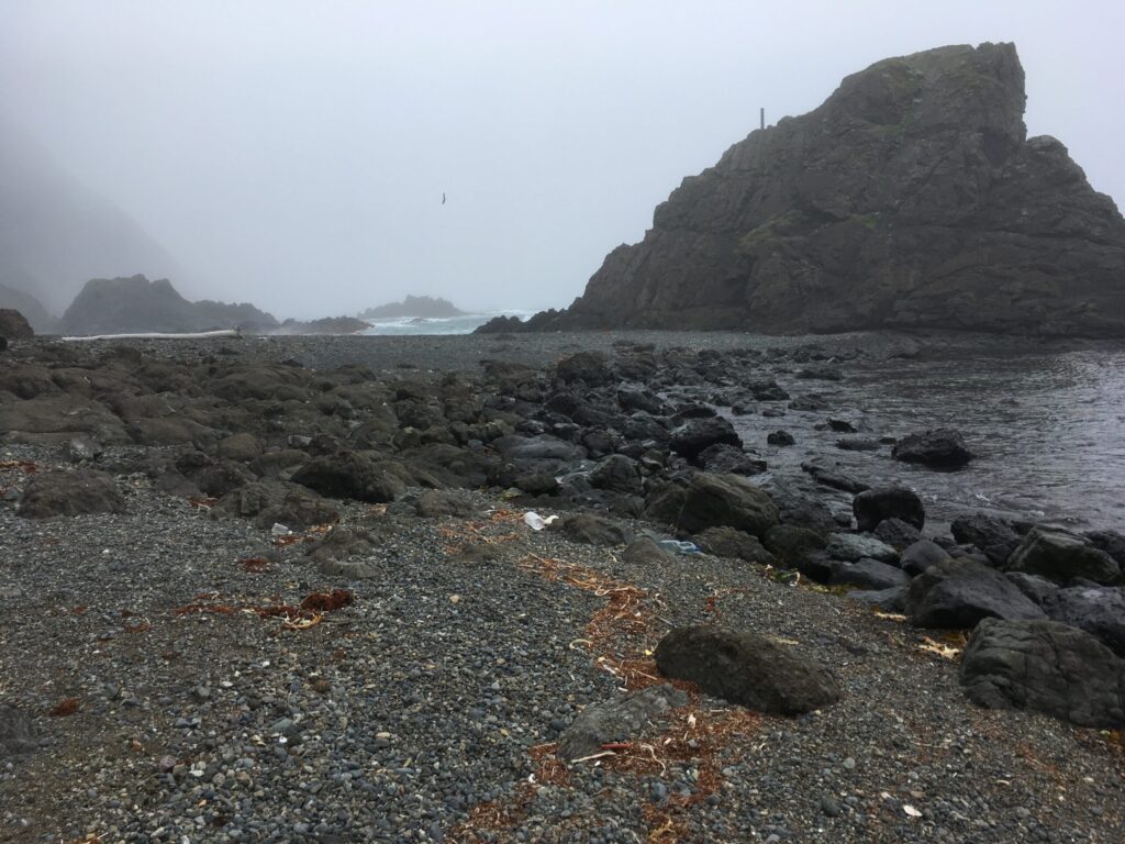 霧に煙る、宇遠内付近の岩場と礫(れき)の海岸
