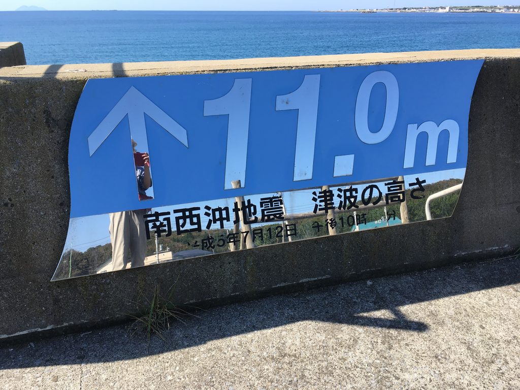 「↑11.0m 南西沖地震 津波の高さ」と書かれた青い看板|青苗の護岸に貼られている|奥尻島