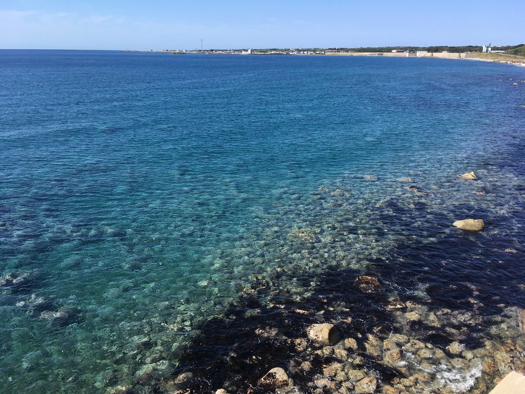 奥尻島の青い海|岩場の先に広がる濃い青と、遠くの島影