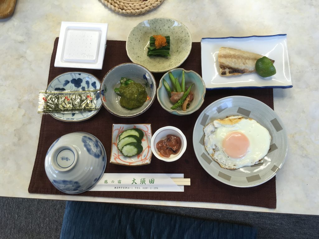 旅の宿大須田の朝食。焼き魚、目玉焼き、青菜のおひたし、小鉢が並ぶ